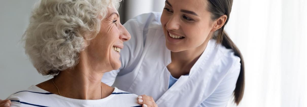 一位老妇人隔着肩膀向一位年轻的护士微笑